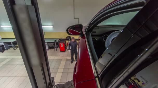 Bil mekaniker röd bil från lift till hjul justering camber kontroll vid reparation service station timelapse — Stockvideo