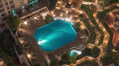 Yüzme havuzlu ve güneşli gökdelenler arasında dinlenme alanı Dubai şehir merkezinde gece vakti