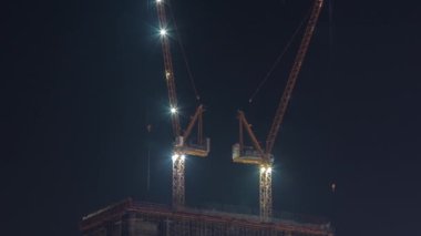 Vinçler, yeni gökdelen zaman çizelgesinin modern soyutlama sahasında geceleri çalışıyorlar.