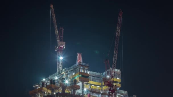 Jeřáby pracující na moderním staveništi nových mrakodrapů v noci — Stock video