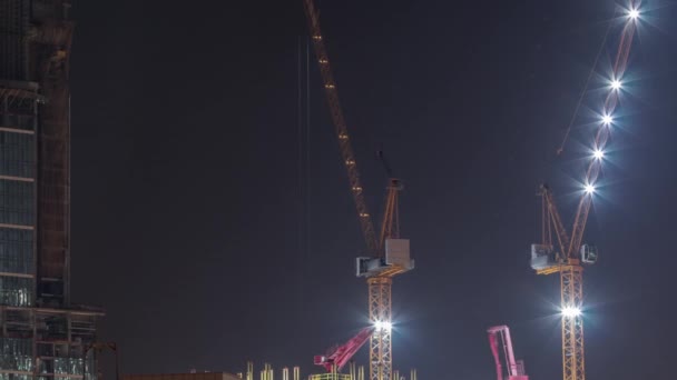 Γερανοί που εργάζονται σε μοντέρνα εργοτάξια του νέου ουρανοξύστη timelapse τη νύχτα — Αρχείο Βίντεο