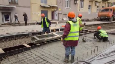 Beton, yol bakımı şantiyesinde çok sayıda işçi ve karıştırıcı zaman ayarlarıyla çalışıyor.