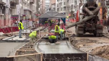 Beton, yol bakımı şantiyesinde çok sayıda işçi ve karıştırıcı zaman ayarlarıyla çalışıyor.