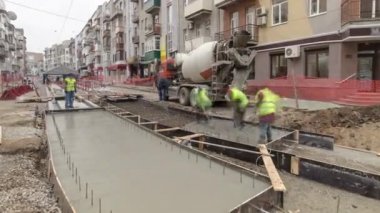 Beton, yol bakımı şantiyesinde çok sayıda işçi ve karıştırıcı zaman ayarlarıyla çalışıyor.