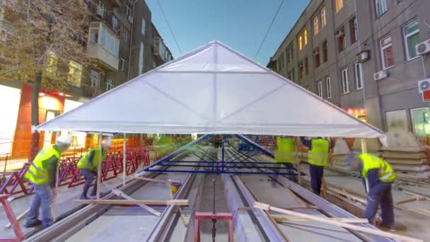 Bouwers maken tent dekking over tramrails in het stadium van hun installatie op de weg timelapse. — Stockvideo