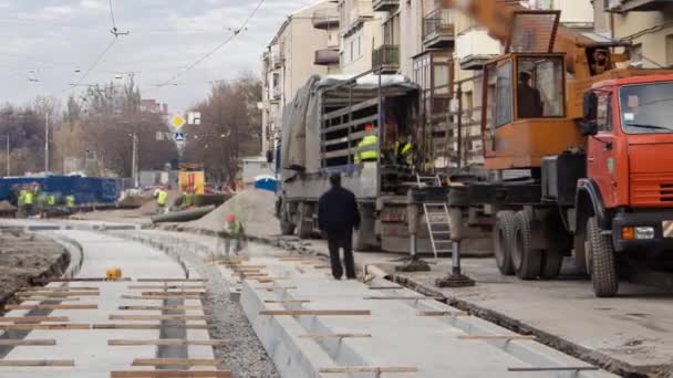 Sporveisskinner under lossing av lastebil med kran på betongplater på kjørebanen . – stockvideo