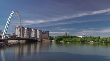 Park timelapse taşıma ve arka planda bulutlar ile Ishim üzerinde köprü. Orta Asya, Kazakistan Astana