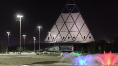 Gece, Astana, Kazakistan 'daki Barış ve Uzlaşma Sarayı' nın yakınlarındaki renkli çeşmeli meydan..