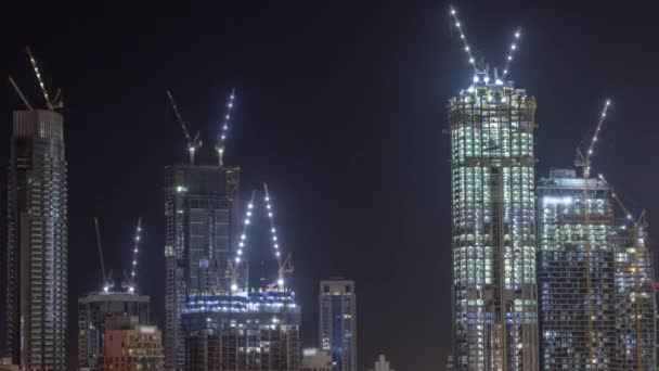 Высокие многоэтажные строящиеся здания и краны в ночное время — стоковое видео