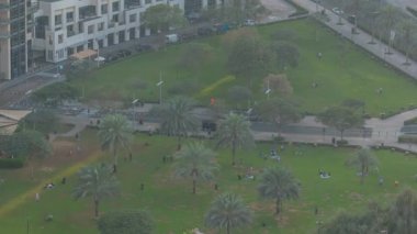 Modern gökdelenlerin önündeki yeşil çimenler ve palmiye ağaçları zaman algısını, Dubai, BAE