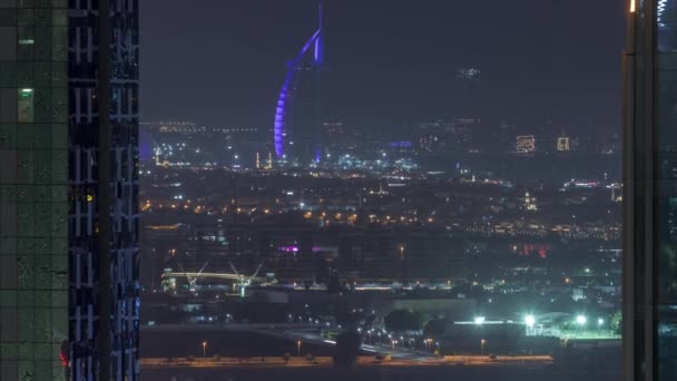 Vista del sitio de construcción, villas y famoso hotel en la línea del horizonte desde Dubai Canal de Agua noche aérea timelapse — Vídeo de stock