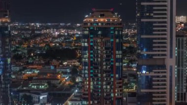 Parlak pencereler, kuleler ve arka plandaki villalar hava gece zaman çizelgesi, Dubai, Birleşik Arap Emirlikleri