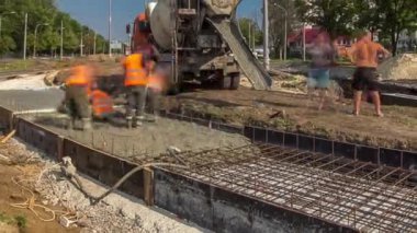 Yol inşaatı için beton dökülüyor. Bir sürü işçi ve mikser zaman ayarlı.
