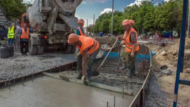 Вирівнювання бетону для будівництва доріг з багатьма робітниками і змішувачем — стокове відео
