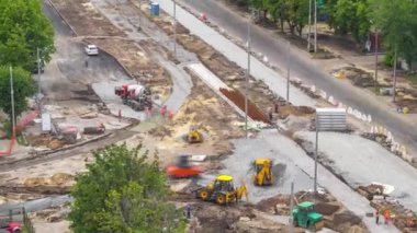 Betondaki karıştırma makinesi yol yapımı için çalışıyor ve çok sayıda işçi çalışıyor.