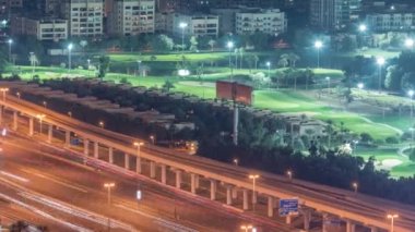 Yeşil çimenli ve göllü golf sahasına hava manzaralı, arkasında villa evleri olan gece zaman ayarlı..