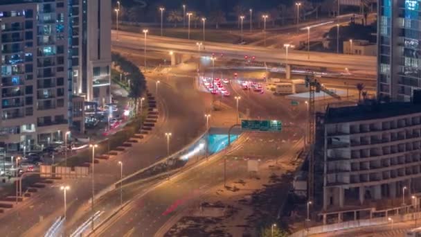 Persimpangan jalan raya besar dengan terowongan di dekat daerah JLT malam udara timelapse. — Stok Video