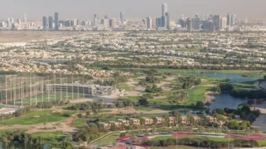Yeşil çimenli ve göllü Golf sahasına hava manzaralı, arkasında villalar olan villalar zaman ayarlı..