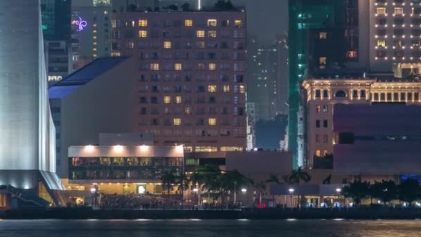 Persone sedute sulle scale vicino al Centro Culturale di Hong Kong con palme e torri sullo sfondo timelapse . — Video Stock