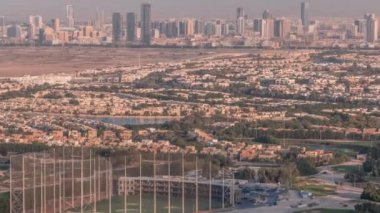 Yeşil çimenli ve göllü Golf sahasına hava manzaralı, arkasında villalar olan villalar zaman ayarlı..