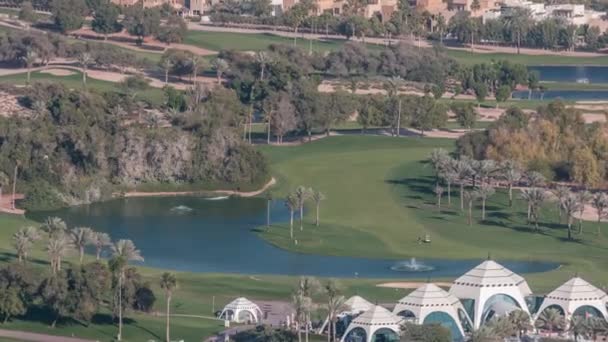 Légi kilátás golfpálya zöld gyep és tavak, villa házak mögötte timelapse. — Stock videók
