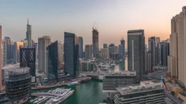Kanal çevresindeki Dubai marina gökdelenlerine gün be gece yüzen teknelerle hava görüntüsü