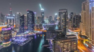 Kanal çevresindeki Dubai marina gökdelenlerine tüm gece yüzen teknelerle hava görüntüsü