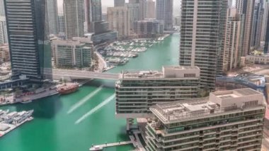 Kanal çevresindeki Dubai marina gökdelenlerine tüm gün yüzen teknelerle hava görüntüsü