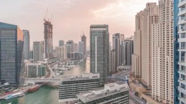 Kanal çevresindeki Dubai marina gökdelenlerine gün be gece yüzen teknelerle hava görüntüsü