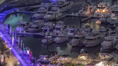 Kanal çevresindeki Dubai yat limanının hava görüntüsü ve gece vakti yüzen tekneler.