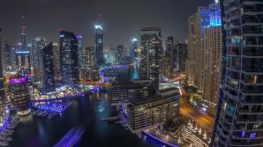 Kanal çevresindeki Dubai marina gökdelenlerine tüm gece yüzen teknelerle hava görüntüsü