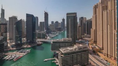 Kanal çevresindeki Dubai marina gökdelenlerine tüm gün yüzen teknelerle hava görüntüsü