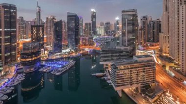 Kanal etrafındaki Dubai marina gökdelenlerine gece gündüz yüzen teknelerle hava görüntüsü.