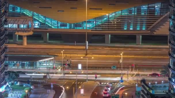 Verkehr auf Kreuzung in der Nähe von Straßenbahnhaltestelle und Ausgang aus U-Bahn-Station auf einem Hintergrund in Dubai Marina Antenne Nacht Zeitraffer — Stockvideo