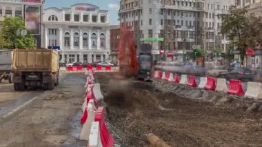 Endüstriyel kamyon yükleyicisi toprağı taşıyor ve bir çöp kamyonuna yüklüyor.