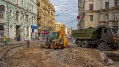 Endüstriyel kamyon yükleyicisi toprağı taşıyor ve bir çöp kamyonuna yüklüyor.