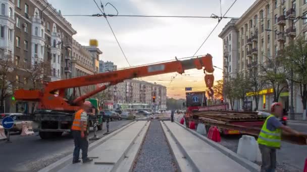 Orangefarbener Bauteleskop-Mobilkran entlädt Straßenbahnschienen aus LKW-Zeitraffer. — Stockvideo