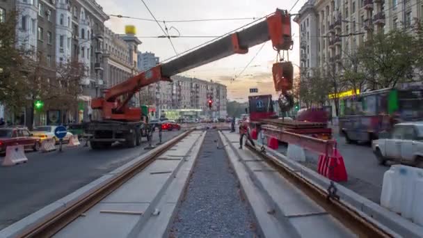 Orangefarbener Bauteleskop-Mobilkran entlädt Straßenbahnschienen aus LKW-Zeitraffer. — Stockvideo
