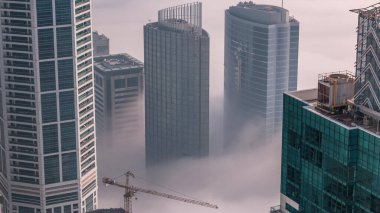 Dubai Marina ve Medya Şehri 'nin ufuk çizgisi ve çatıları üzerindeki nadir kış sisleriyle kaplı kuleler. Üst görünüm bulutların üstünde. Dubai, BAE
