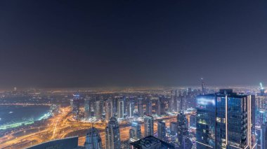 Dubai Marina Panorama 'sı JLT gökdelenleri ve golf sahası ile tüm gece boyunca, Dubai, Birleşik Arap Emirlikleri. Sisi olan kulelerin üzerinden hava görüntüsü. Işıklar sönerken şehrin ufuk çizgisi
