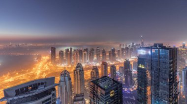 Dubai Marina Panoraması 'nda JLT gökdelenleri ve golf sahası gece gündüz geçiş zamanı, Dubai, Birleşik Arap Emirlikleri. Yukarıdan hava manzarası sisli bir sabah. Çatıları olan şehir silüeti