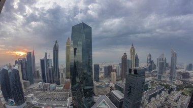 Sheikh Zayed karayolu zaman çizelgesinde Dubai 'deki finans merkezinde gün batımına sahip gelecekçi gökdelenlerin manzarası. Yukarıdan gökyüzü turuncu bulutlu