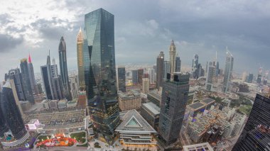 Gün batımından sonra Dubai 'deki finans merkezindeki gökdelenlerin panoramasında trafik günden geceye geçiş zamanlarında. Bulutlu gökyüzü ile yukarıdan hava görüntüsü