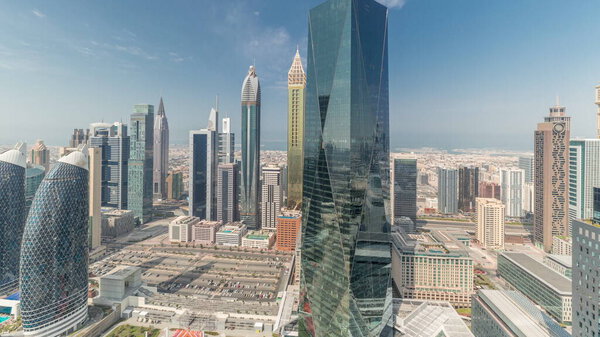 Panorama showing many futuristic skyscrapers in financial district business center in Dubai on Sheikh Zayed road timelapse. Aerial view from above with clouds