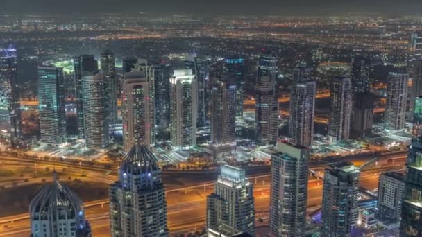 Dubai Marina e JLT distrito com tráfego na estrada entre arranha-céus aéreo noite timelapse. — Vídeo de Stock