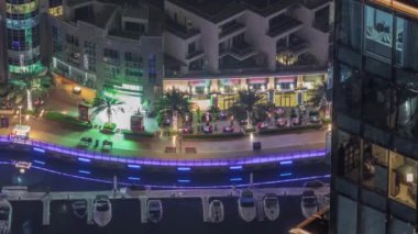 Dubai Marina 'daki hava manzarası palmiyeler ve yatlar ile aydınlatılmış gezinti alanı..