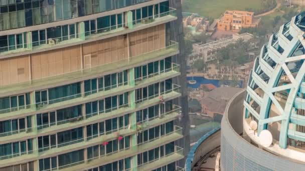 Muži myjí okna ve výšce na moderním mrakodrapu. Pláž JBR s turisty — Stock video
