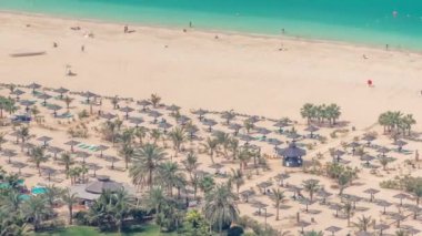 Kalabalık JBR plajında güneş ve denizin tadını çıkaran turistler şemsiyelerin altında oturuyordu.