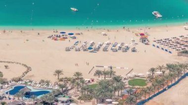 Kalabalık JBR plajında güneş ve denizin tadını çıkaran turistler şemsiyelerin altında oturuyordu.