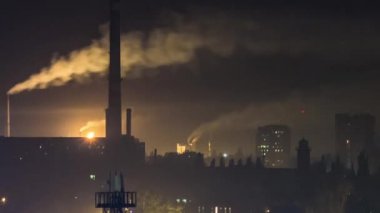 Dumanlı borular ve konut binaları gece zaman ayarlı.